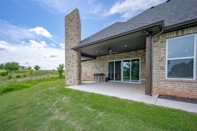 rear view of property featuring ceiling fan, a patio area, and a yard