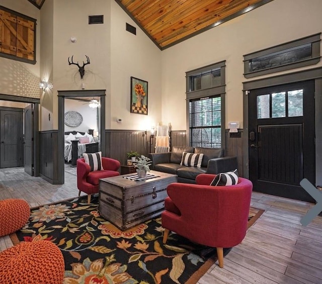 living room featuring wooden walls, light hardwood / wood-style floors, wooden ceiling, and high vaulted ceiling