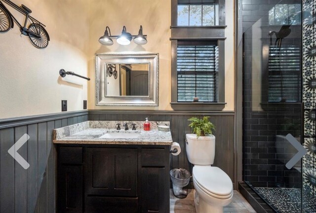 bathroom with a tile shower, vanity, and toilet