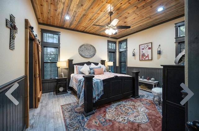 bedroom featuring hardwood / wood-style floors, ceiling fan, a barn door, and multiple windows