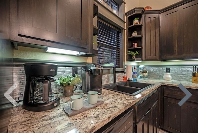 kitchen featuring dark brown cabinets, light stone counters, sink, and tasteful backsplash