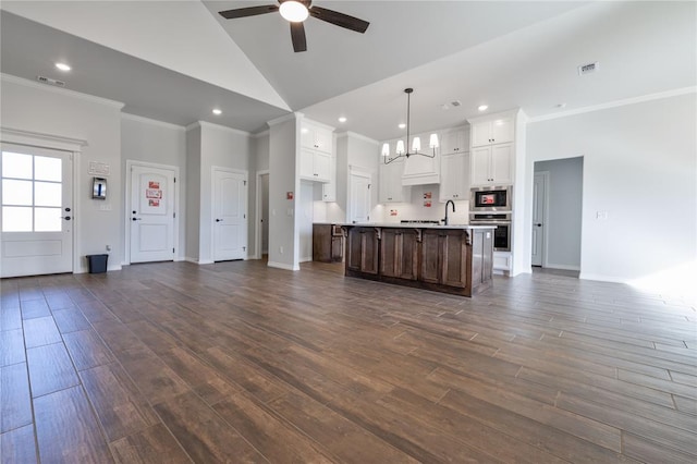 kitchen with a kitchen island with sink, ceiling fan with notable chandelier, dark hardwood / wood-style floors, decorative light fixtures, and white cabinetry