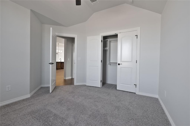 unfurnished bedroom featuring carpet flooring, vaulted ceiling, and a closet