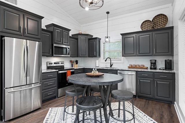 kitchen with dark wood-type flooring, stainless steel appliances, light stone counters, pendant lighting, and lofted ceiling