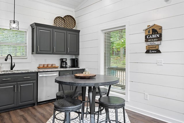 kitchen with dishwasher, dark hardwood / wood-style floors, wooden walls, and sink