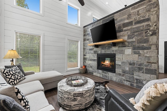 living room featuring wood walls, dark hardwood / wood-style flooring, a fireplace, and a high ceiling