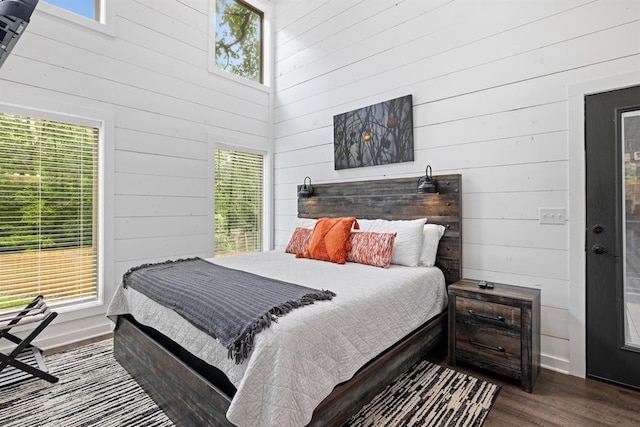 bedroom featuring hardwood / wood-style floors, wood walls, and a high ceiling