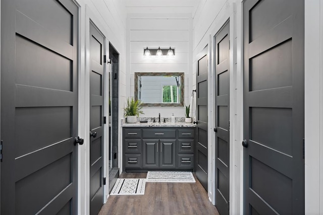 bathroom featuring hardwood / wood-style floors, vanity, and wood walls