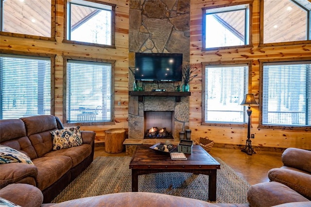 living room with a fireplace, concrete flooring, a high ceiling, and wood walls