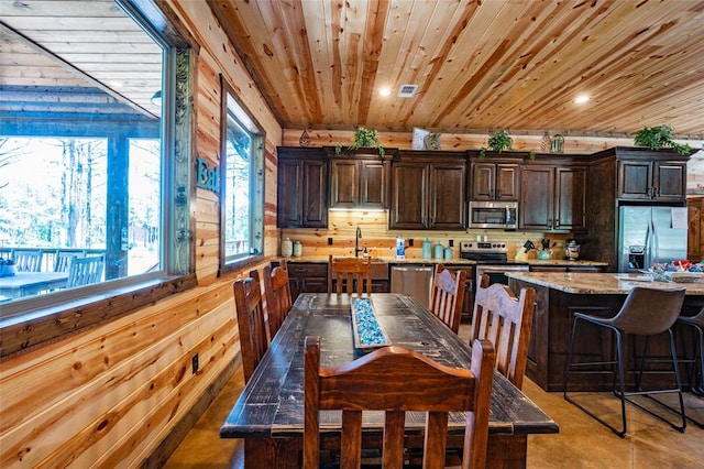 dining area featuring plenty of natural light, wood ceiling, and wood walls