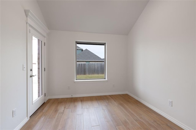 empty room featuring light wood-type flooring and vaulted ceiling