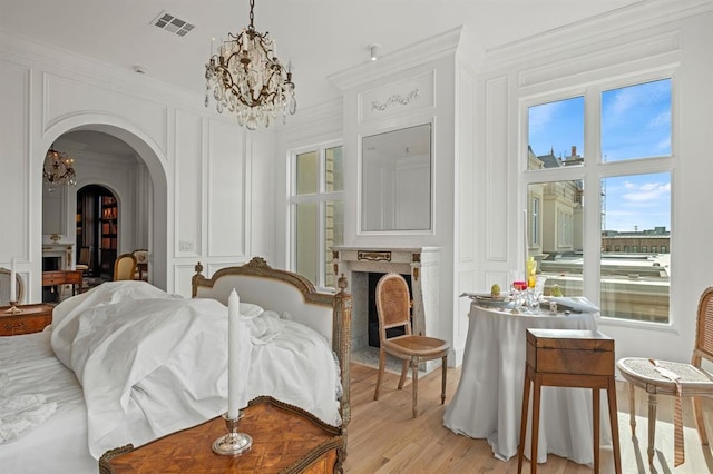 living area with a fireplace, light hardwood / wood-style flooring, a chandelier, and ornamental molding