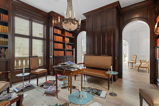 sitting room featuring built in shelves, light hardwood / wood-style floors, and a notable chandelier