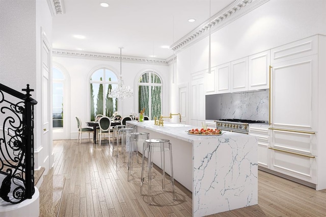 kitchen featuring white cabinetry, a kitchen island, light stone counters, and light wood-type flooring