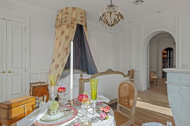 dining area with light wood-type flooring, crown molding, and a notable chandelier