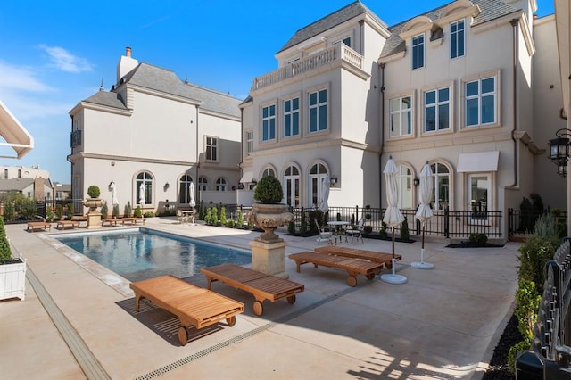 back of house with a fenced in pool and a patio