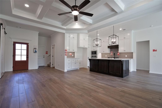 kitchen with backsplash, crown molding, pendant lighting, hardwood / wood-style floors, and an island with sink