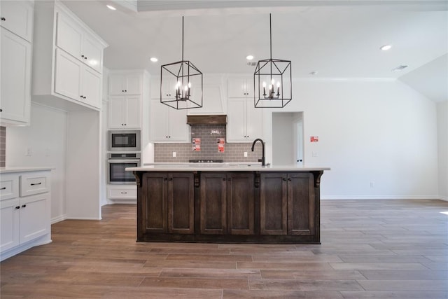 8800 Tyrion Dr, Edmond, OK 73007 - kitchen with black appliances, a chandelier, light countertops, light wood finished floors, and white cabinetry