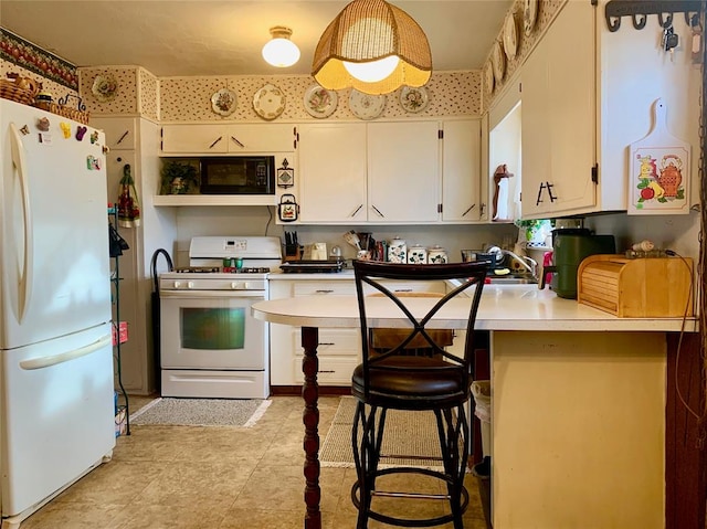 kitchen featuring white cabinets, kitchen peninsula, white appliances, and a breakfast bar area