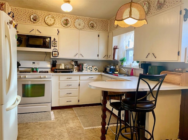 kitchen with pendant lighting, white appliances, white cabinets, kitchen peninsula, and a breakfast bar area