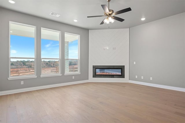 unfurnished living room featuring ceiling fan, light hardwood / wood-style floors, and a fireplace