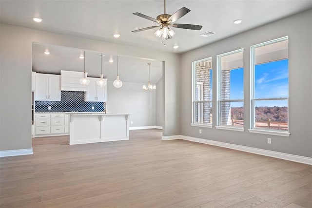 kitchen featuring decorative backsplash, decorative light fixtures, light hardwood / wood-style flooring, white cabinets, and a center island