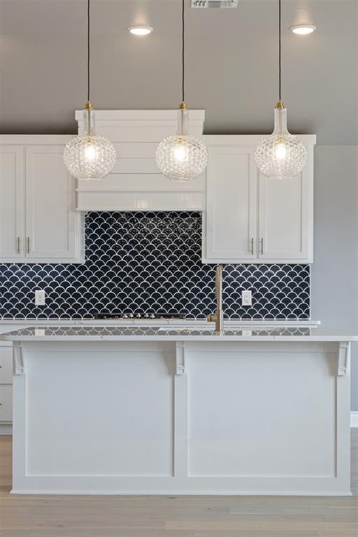 kitchen with pendant lighting, backsplash, and white cabinetry