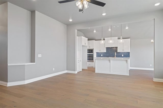 kitchen featuring decorative light fixtures, backsplash, light hardwood / wood-style floors, and white cabinetry