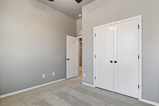 unfurnished bedroom with light carpet, a closet, and ceiling fan