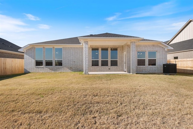 rear view of property with a lawn and cooling unit