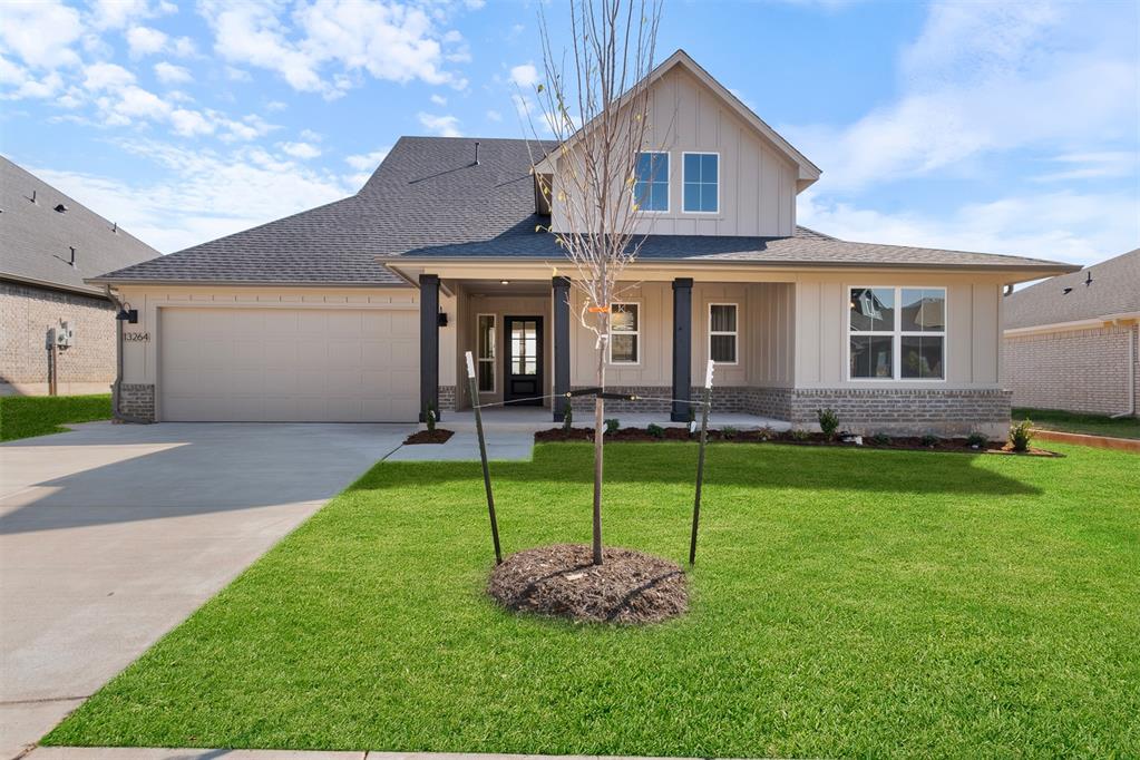 view of front of house featuring covered porch, a garage, and a front lawn