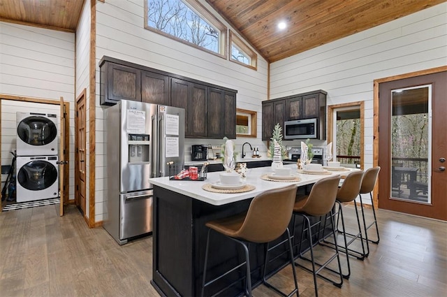 kitchen with stainless steel appliances, high vaulted ceiling, plenty of natural light, and an island with sink