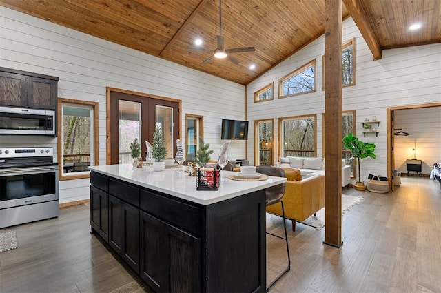 kitchen featuring wood ceiling, an island with sink, pendant lighting, and appliances with stainless steel finishes