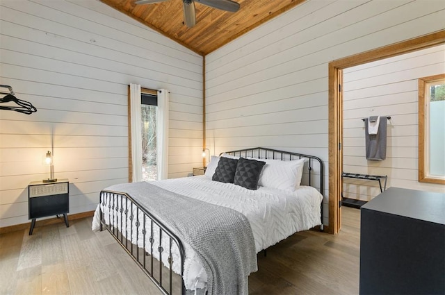 bedroom featuring wooden walls, vaulted ceiling, hardwood / wood-style flooring, ceiling fan, and wood ceiling