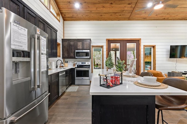 kitchen with sink, a center island, stainless steel appliances, wood walls, and wood ceiling