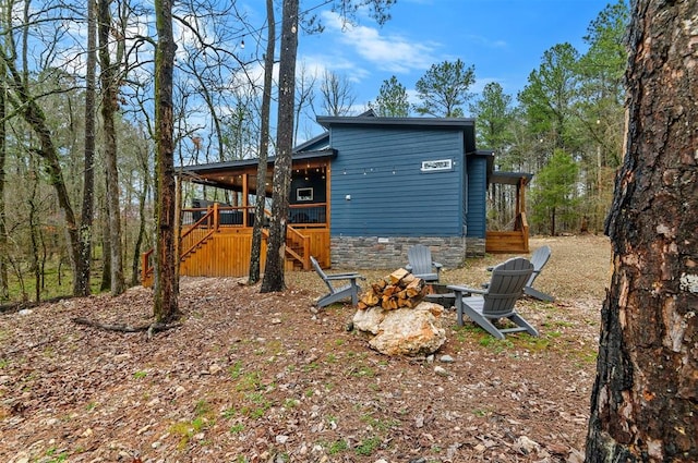 back of property featuring a fire pit and a wooden deck