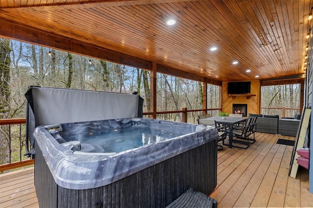 wooden deck featuring a hot tub and an outdoor fireplace