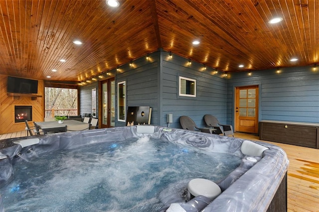 wooden deck featuring a hot tub and an outdoor fireplace