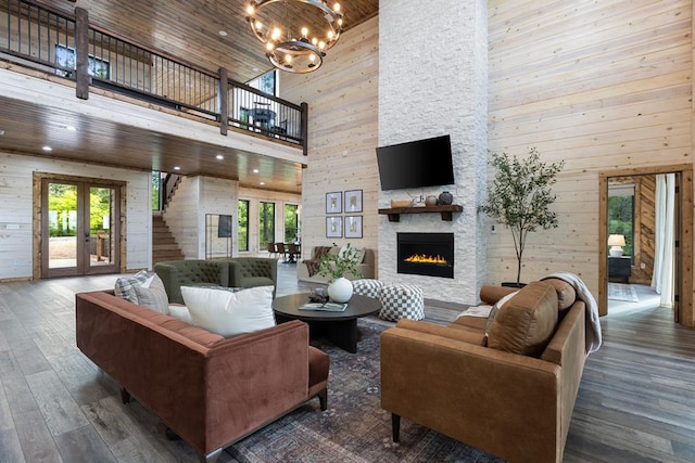 living room with a stone fireplace, a wealth of natural light, wooden walls, and high vaulted ceiling