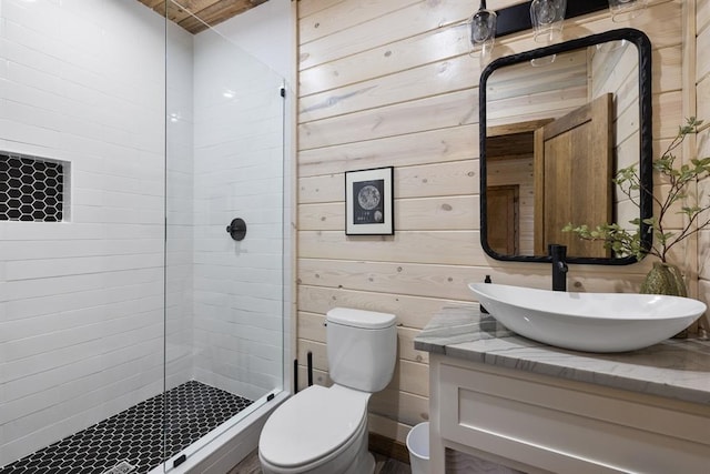 bathroom with wood walls, vanity, a shower with shower door, and toilet