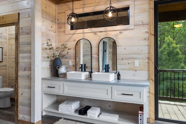 bathroom featuring vanity, wood walls, toilet, and wood-type flooring