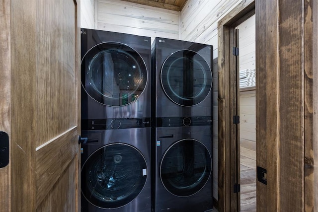 laundry room with wood walls and stacked washer and clothes dryer