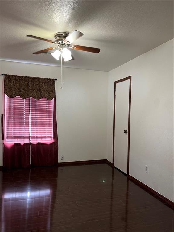 empty room featuring a textured ceiling, dark hardwood / wood-style floors, and ceiling fan