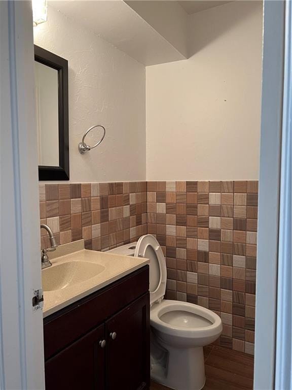 bathroom with hardwood / wood-style flooring, vanity, toilet, and tile walls