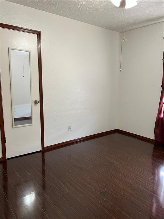 empty room with dark hardwood / wood-style flooring and a textured ceiling