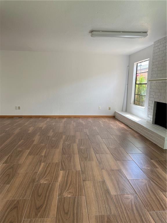 unfurnished living room featuring hardwood / wood-style flooring and a brick fireplace