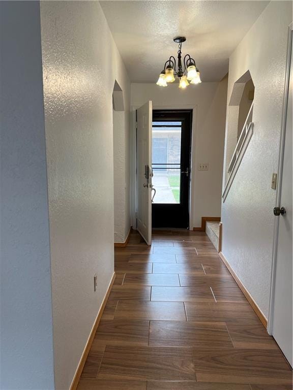 doorway with dark hardwood / wood-style floors and an inviting chandelier