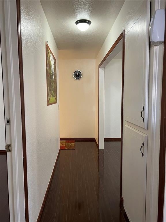 hallway featuring a textured ceiling and dark wood-type flooring