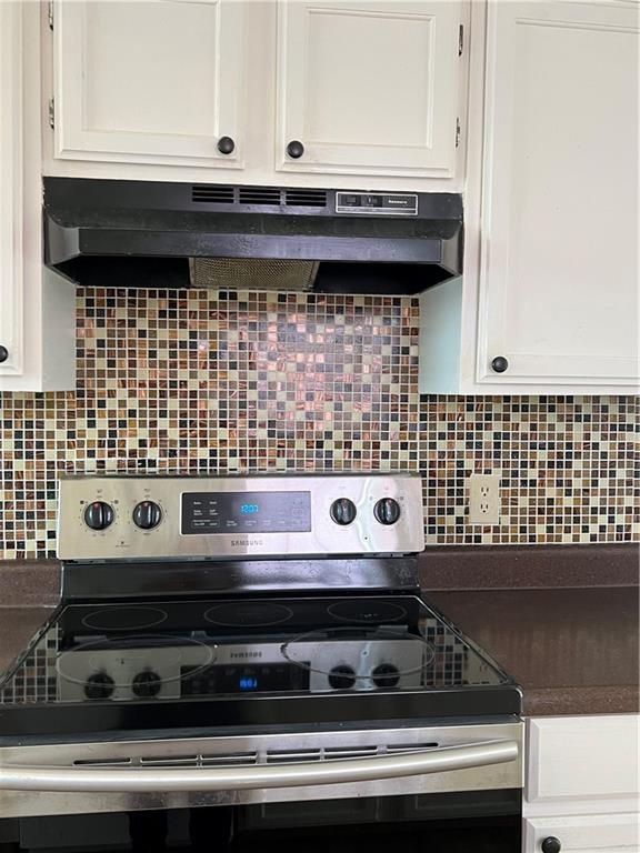 kitchen featuring backsplash, electric stove, and white cabinets