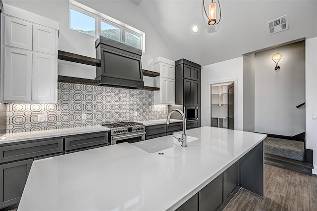 kitchen featuring white cabinets, pendant lighting, backsplash, and stainless steel stove